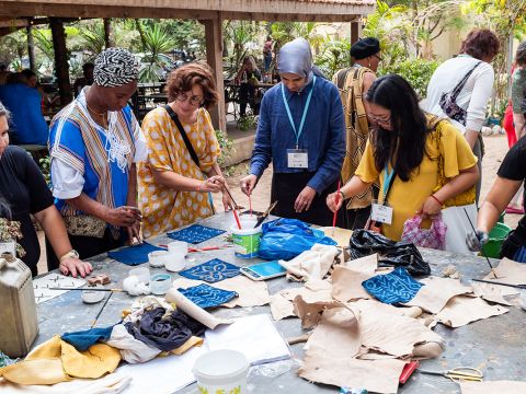 Left side of the image has participants creating designs on indigo cloth, while the right side has participants creating designs on bogolon cloth.