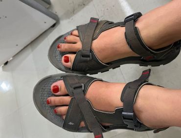 Two feet stretched out wearing brown leather sandals.